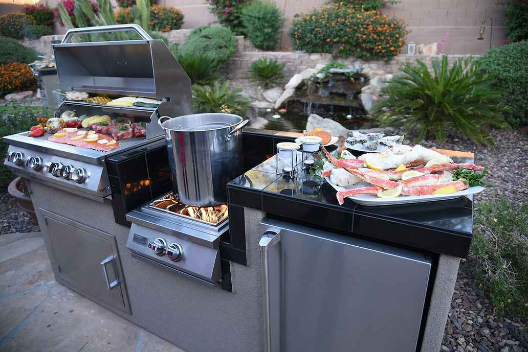Angled view of the Kokomo island with open grill, pot on the wok burner and seafood on the countertop.