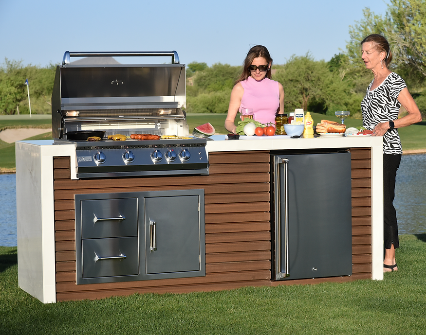 Two people preparing food beside the open grill on the Kokomo waterfall-edge outdoor kitchen island.