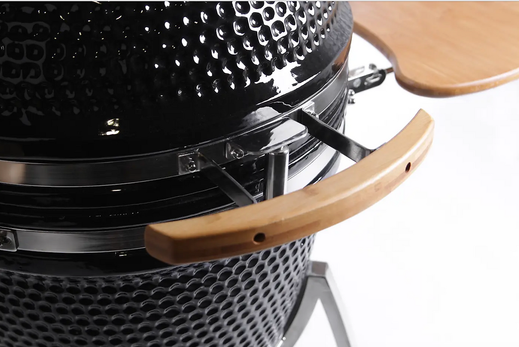 Close-up of the wooden lid handle on a black ceramic kamado grill.