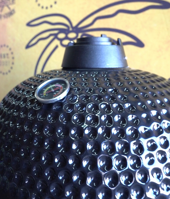 Close-up of the black ceramic grill lid showing the top airflow vent and built-in thermometer.