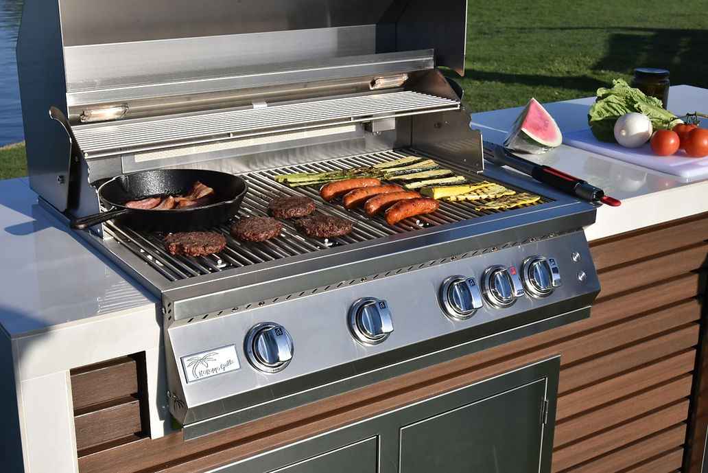 Close-up of the Kokomo built-in grill cooking meat and vegetables beside the island countertop.