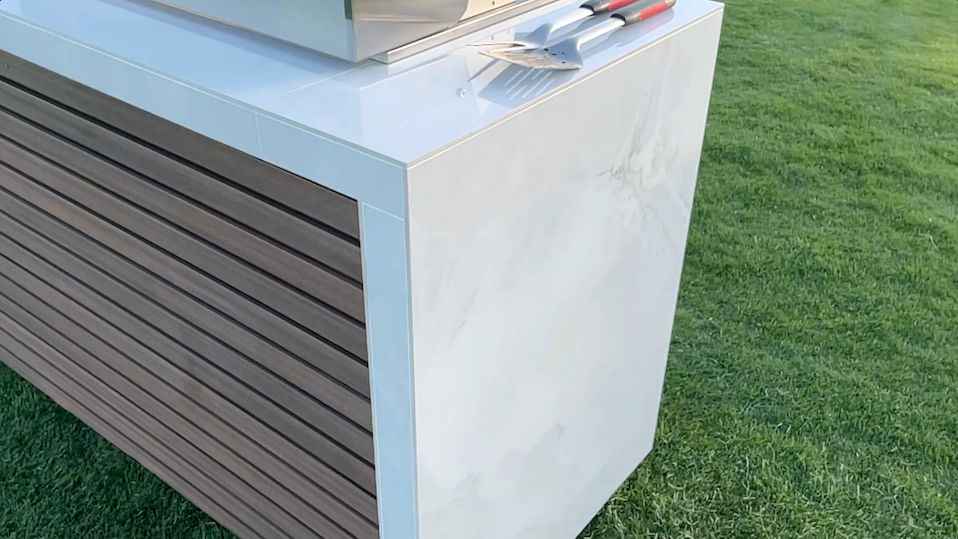 Close-up of the island’s white waterfall countertop edge and horizontal-panel exterior.