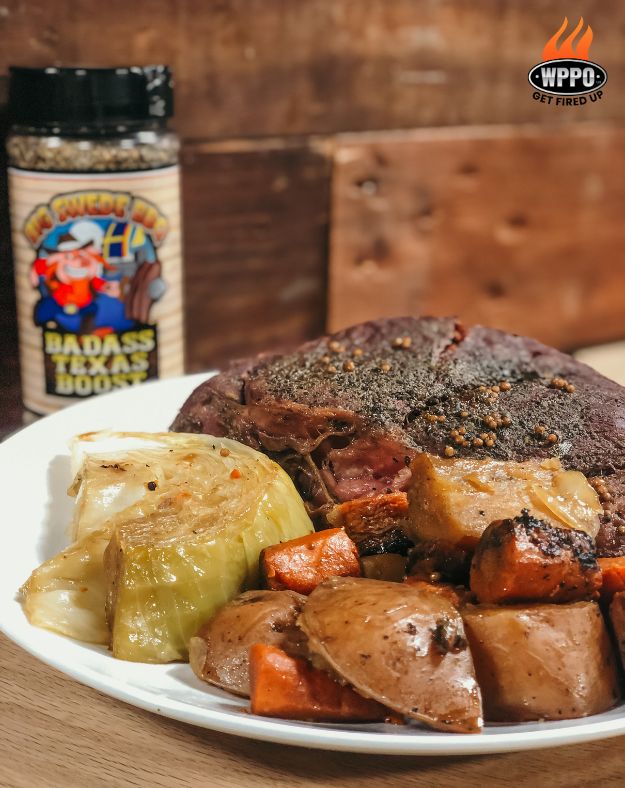 Plate of roasted meat, potatoes, carrots and onion with a seasoning bottle in the background.