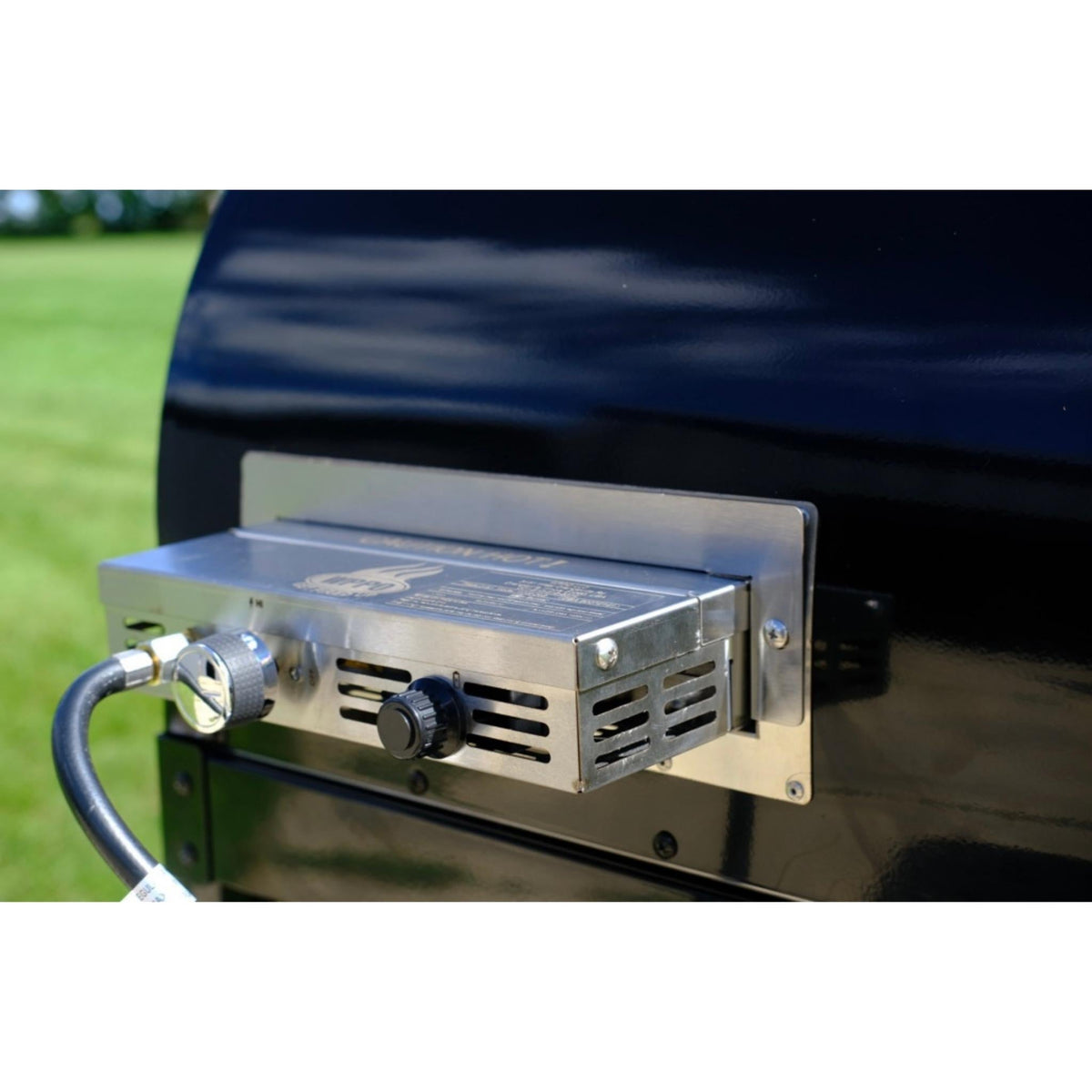 Close-up of the oven’s side-mounted gas attachment with hose connection and control knob.
