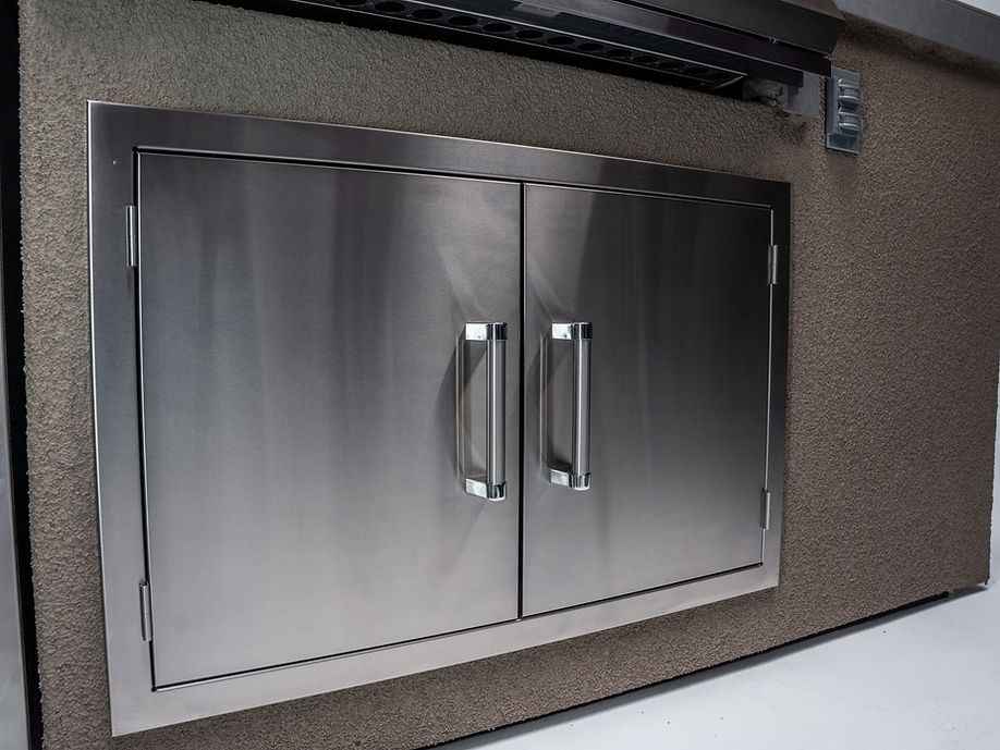 Close-up of the double stainless steel access doors beneath the built-in grill.