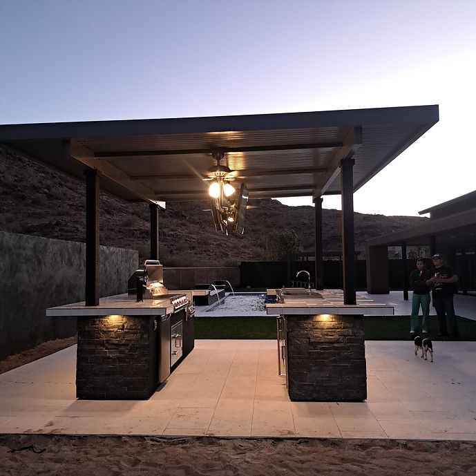 View through the Kokomo outdoor kitchen’s central opening with grill, sink, covered counters and ceiling fan.