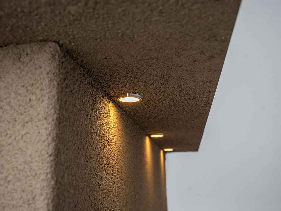 Close-up of illuminated lights beneath the outdoor kitchen island’s countertop overhang.