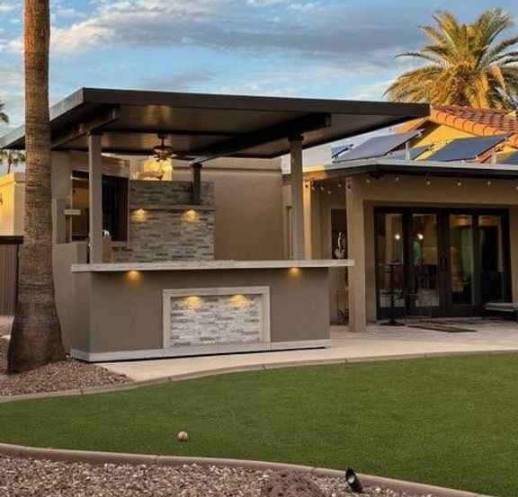 Side view of Kokomo Bermuda covered outdoor kitchen beside a lawn, showing bar counter and lighting.