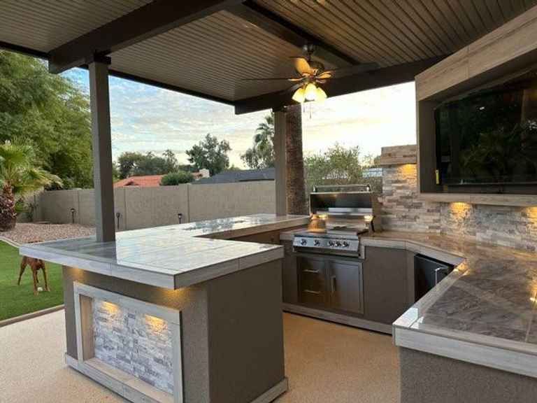 Interior view of the covered Kokomo Bermuda kitchen with built-in grill, TV, ceiling fan and counters.