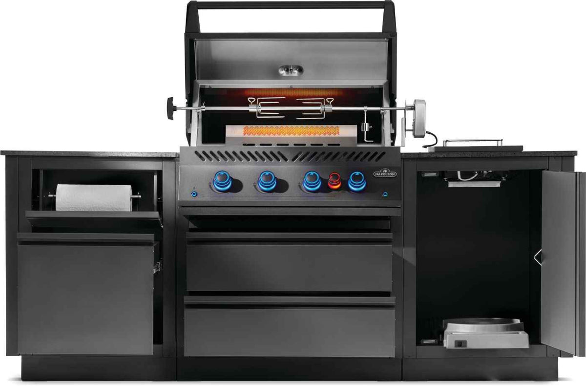 Front view of Napoleon OASIS outdoor kitchen with rotisserie, glowing rear burner, open drawers and tank cabinet.