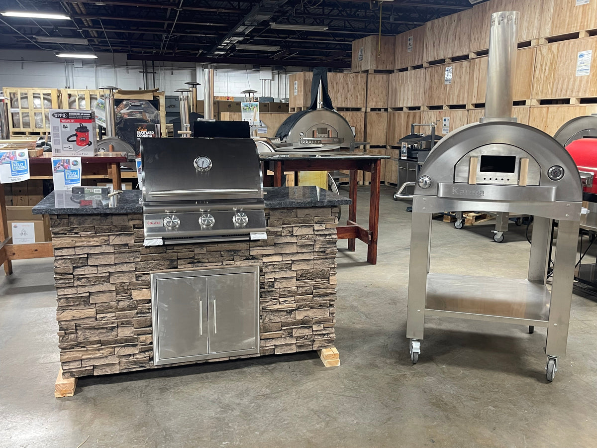 WPPO outdoor kitchen island with Blaze grill beside a separate wheeled pizza oven in a showroom.