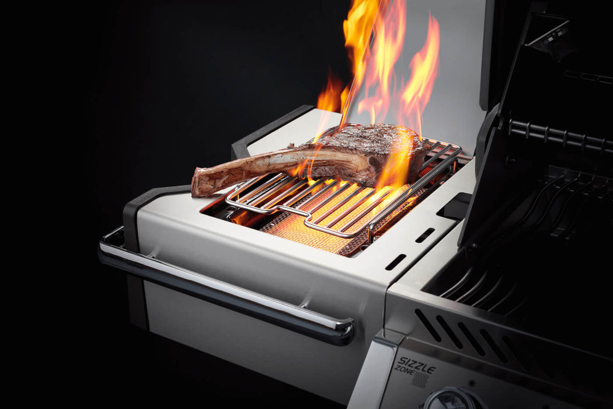 Close-up of a steak cooking over flames on a Napoleon infrared side burner.