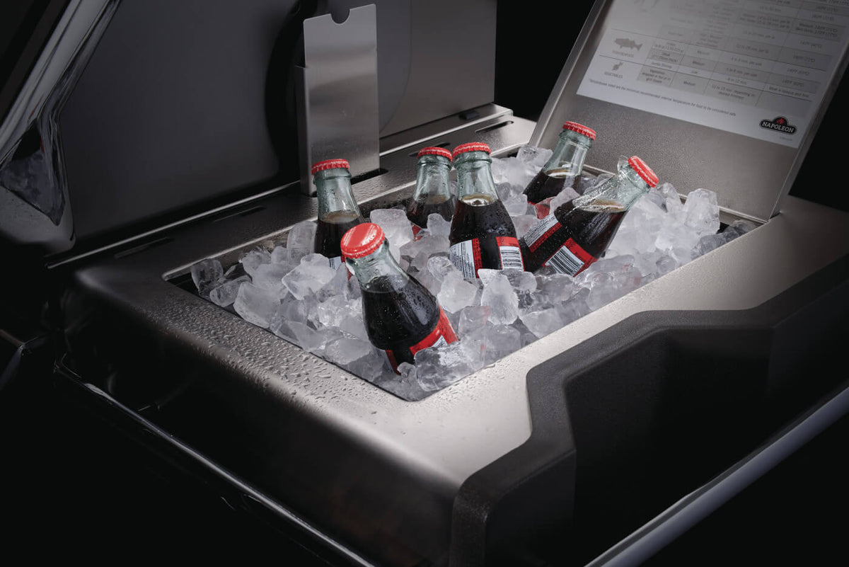 Close-up of bottled drinks and ice in a grill side-shelf compartment.