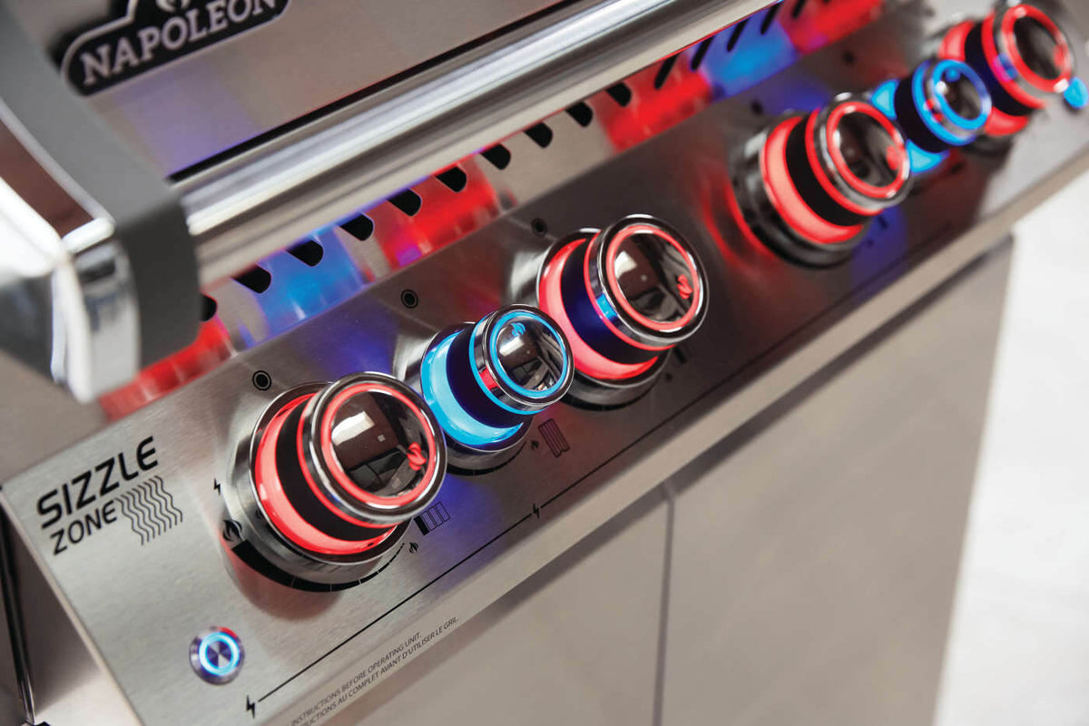 Close-up of Napoleon grill control knobs illuminated in red and blue.