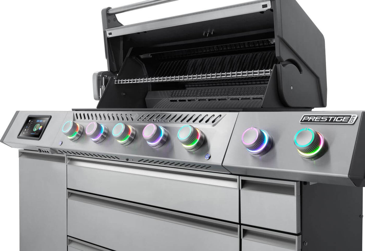 Angled view of Prestige PRO 665 Elite gas grill with lid open, touchscreen and multicolored illuminated knobs.