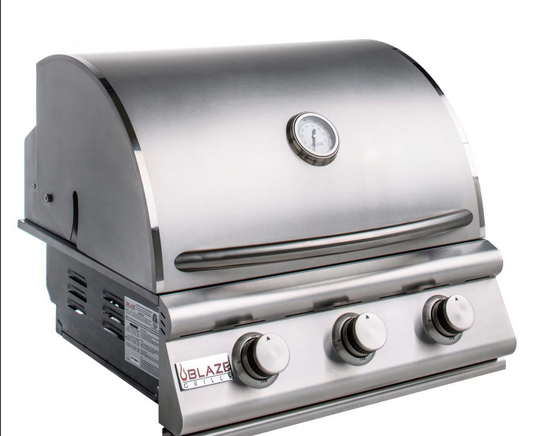 Angled view of Blaze three-burner built-in grill with closed stainless steel hood and analog thermometer.